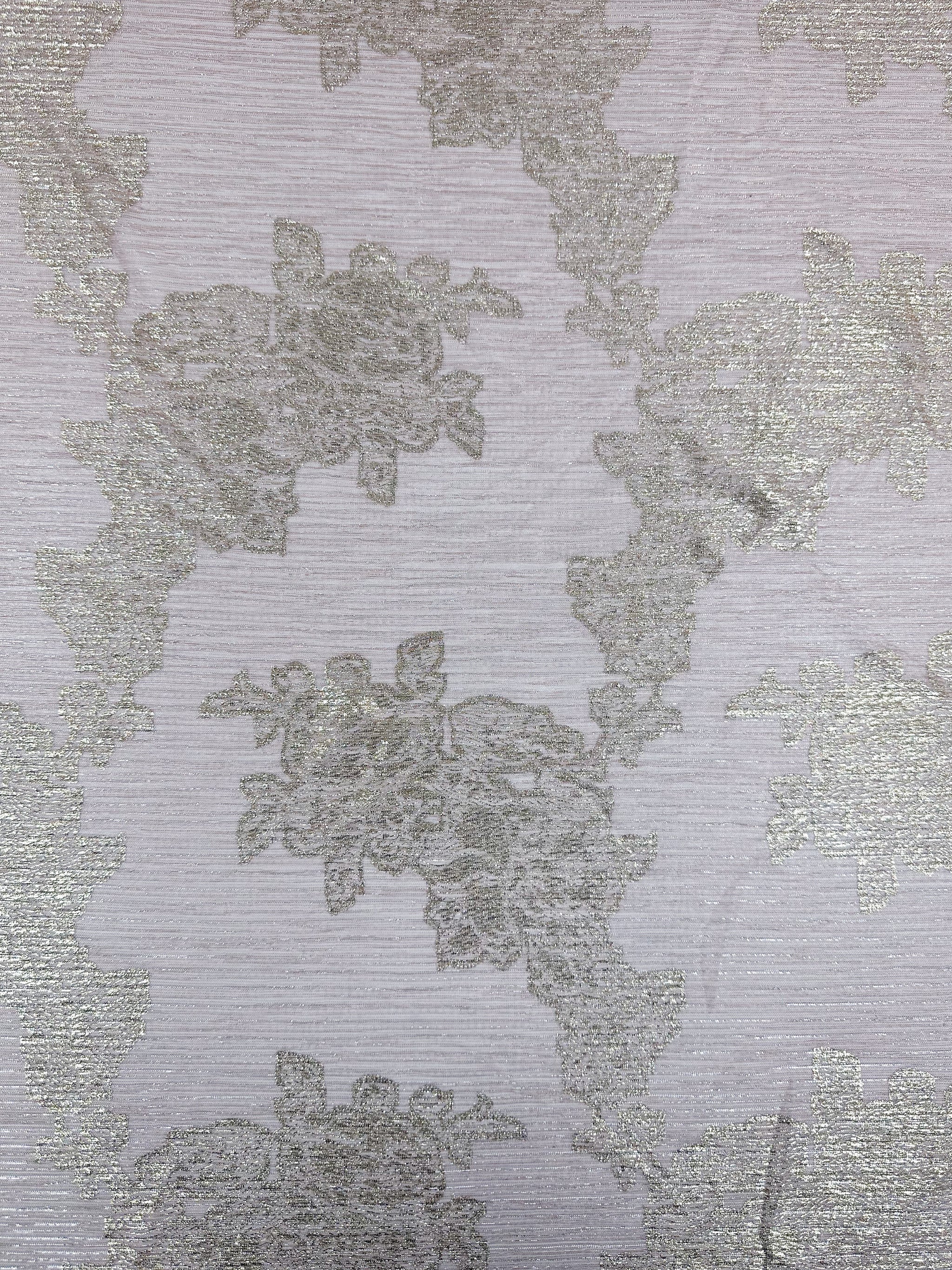 Close-up of the Metallix Pleat - Gold Leaf fabric by Super Cheap Fabrics. This light beige polyester textile features intricate floral embroidery. The elegant pattern of flowers and leaves is subtly highlighted with hints of baby pink, adding sophistication to its lightweight appearance.