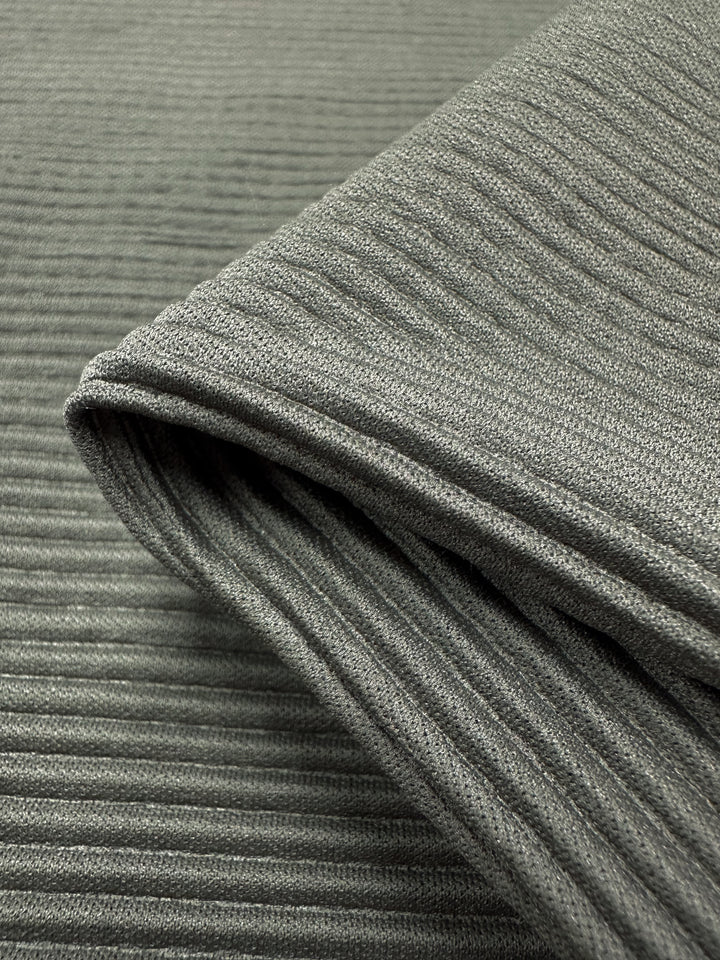 Close-up of Pleat - Pewter - 140cm fabric by Super Cheap Fabrics. This gray ribbed polyester material features a lightweight, textured surface with parallel ridges creating vertical lines.