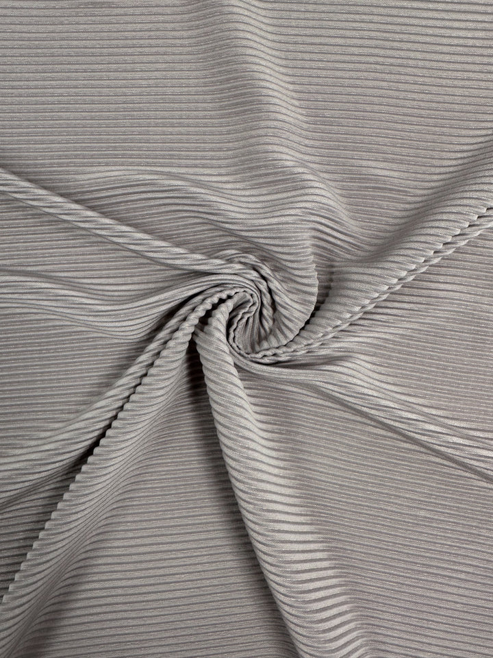 Close-up of "Pleat - Violet Ice - 140cm" by Super Cheap Fabrics, displaying a spiral pattern in grey ribbed polyester. The fabric has a textured surface, subtle sheen, and medium thickness, with a hue reminiscent of violet ice.