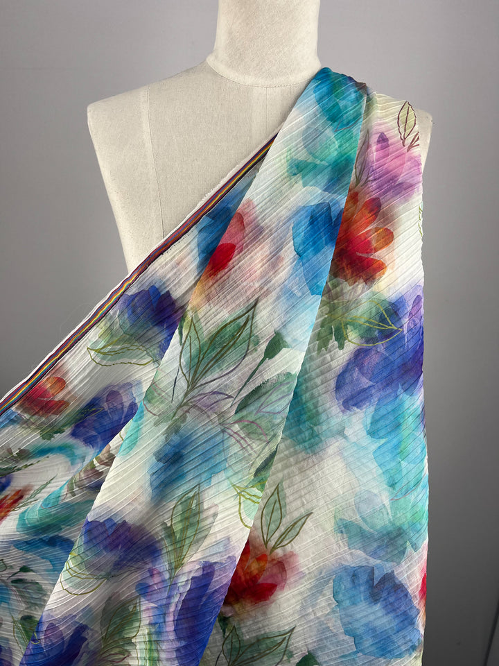The Textured Tencel - Dream Flor - 136cm by Super Cheap Fabrics showcases a luxurious, sustainable design with an asymmetrical floral pattern. Vibrant blue, red, and green hues pop against a multicolored light background.