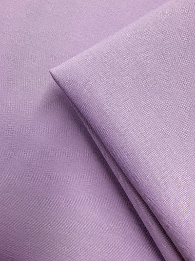 Close-up of Milano Ponte - Viola - 160cm by Super Cheap Fabrics, showing folded light purple fabric with a fine weave, soft smooth texture, and gentle sheen. This heavy weight stretch ponte is ideal for structured garments.