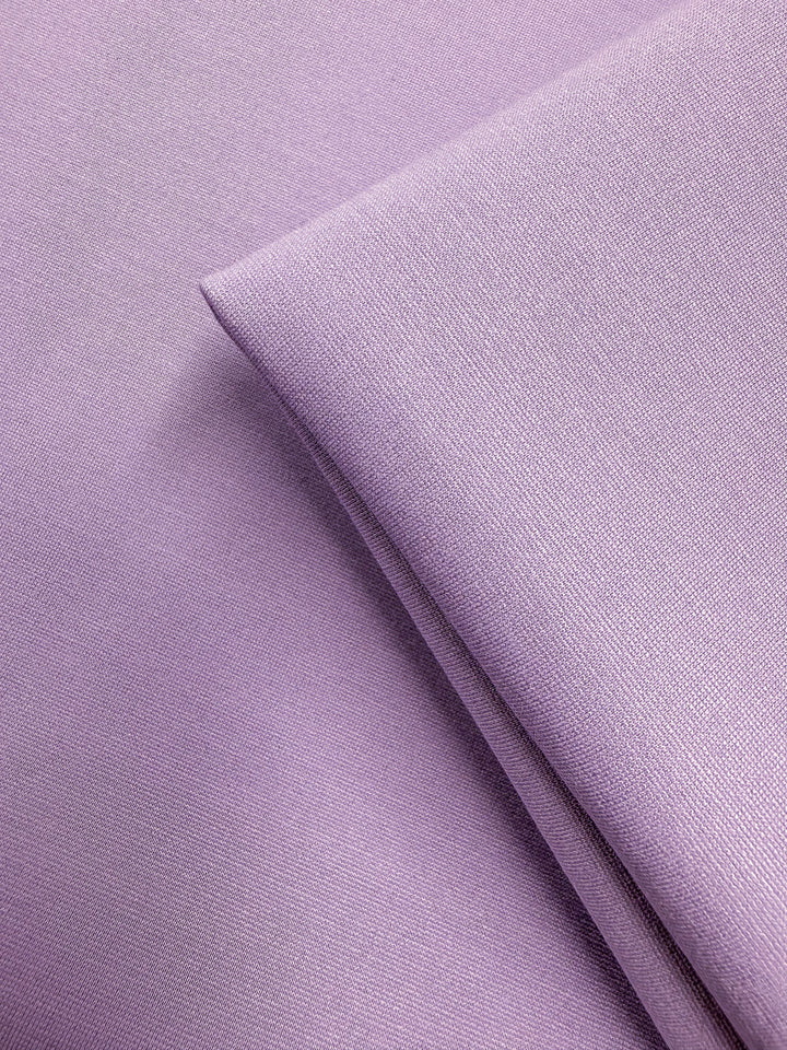 Close-up of Milano Ponte - Viola - 160cm by Super Cheap Fabrics, showing folded light purple fabric with a fine weave, soft smooth texture, and gentle sheen. This heavy weight stretch ponte is ideal for structured garments.
