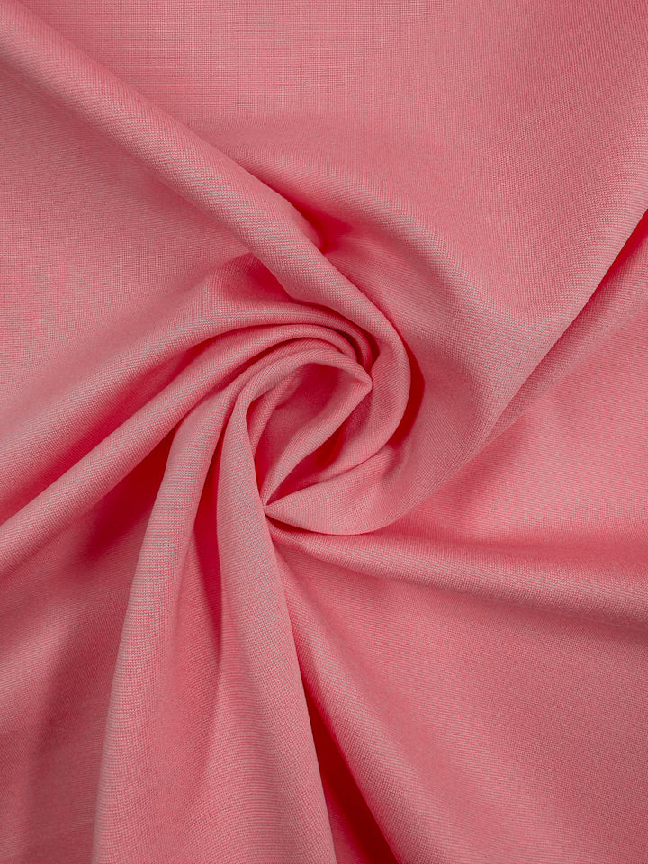 A close-up of Milano Ponte - Flamingo Pink by Super Cheap Fabrics (160cm), showing its smooth texture and spiral-gathered folds. The 4-way stretch fabric highlights flexibility and soft shadows.