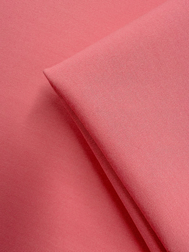 A close-up of Super Cheap Fabrics’ Milano Ponte in Flamingo Pink (160cm), showing two overlapping pieces with a smooth texture, fine weave, and subtle 4-way stretch.