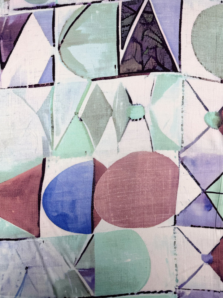 Mercerised Rayon - Mid Mod Mirage by Super Cheap Fabrics features abstract circles, triangles, and rectangles in pastel green, purple, and blue with dark outlines on a textured background—perfect for breathable lightweight projects. Width: 150cm.
