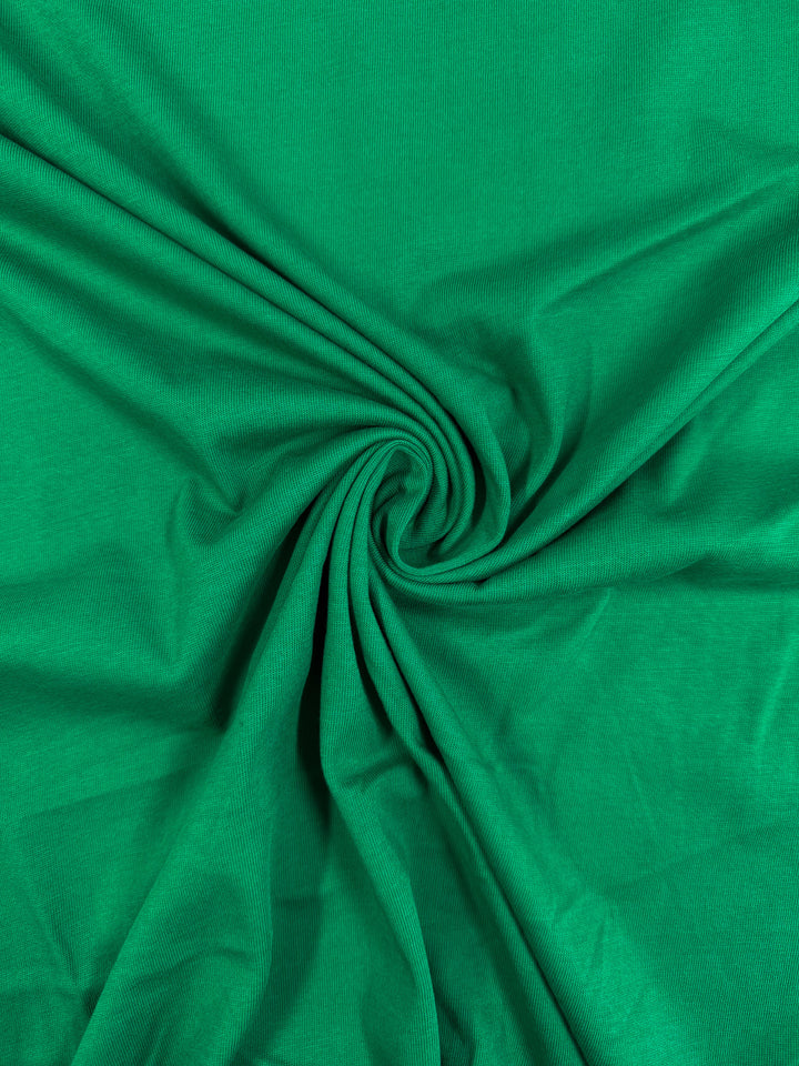 Super Cheap Fabrics’ Cotton Jersey - Parakeet - 165cm is a soft, light to medium weight 100% cotton fabric. Its green jersey texture forms spiral folds radiating from the center, ideal for comfortable clothing.
