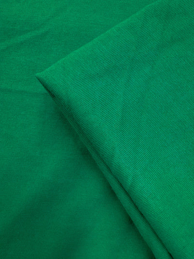 A close-up of two overlapping pieces of Super Cheap Fabrics’ Cotton Jersey - Parakeet (165cm), highlighting the texture and weave of this light to medium weight, 100% cotton material.