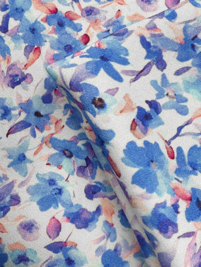 Close-up of Super Cheap Fabrics’ Mercerised Rayon - Bluebell Drift (150cm): lightweight, breathable material with a watercolor floral pattern in blue, purple, and pink on white, featuring soft overlapping flower shapes.