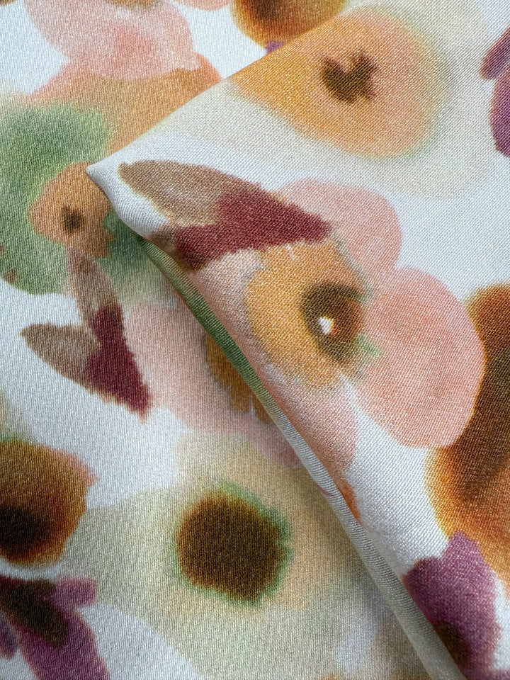 A close-up of Super Cheap Fabrics’ Mercerised Rayon - Blushed Camellia (150cm), featuring a lightweight fabric with a watercolor floral pattern in soft pink, green, brown, and yellow on white.