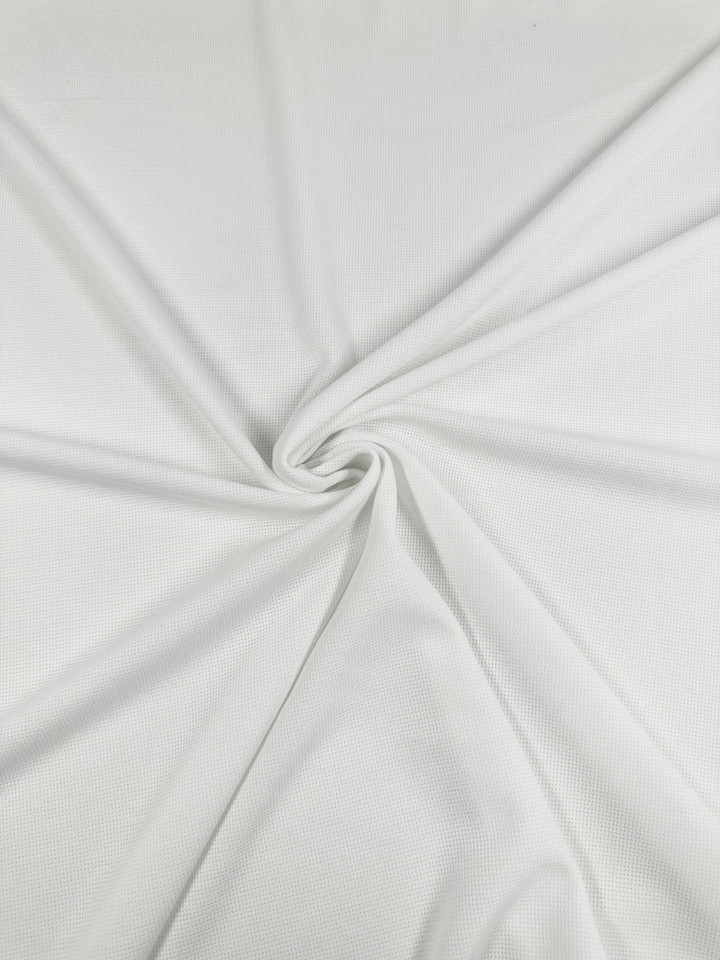 The Super Cheap Fabrics Waffle Knit - White - 152cm features a subtle grid pattern. When arranged in folds radiating from a central twist, it creates a spiral effect and enhances its three-dimensional look.
