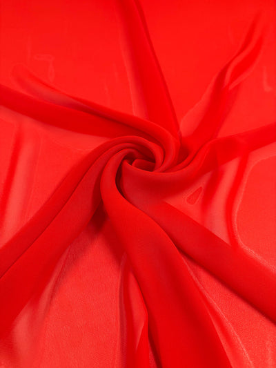 Hi-Multi Chiffon - Flame Scarlet by Super Cheap Fabrics is a bright red, lightweight, and slightly transparent sheer fabric arranged in a swirl to highlight its smooth texture. Width: 150cm.