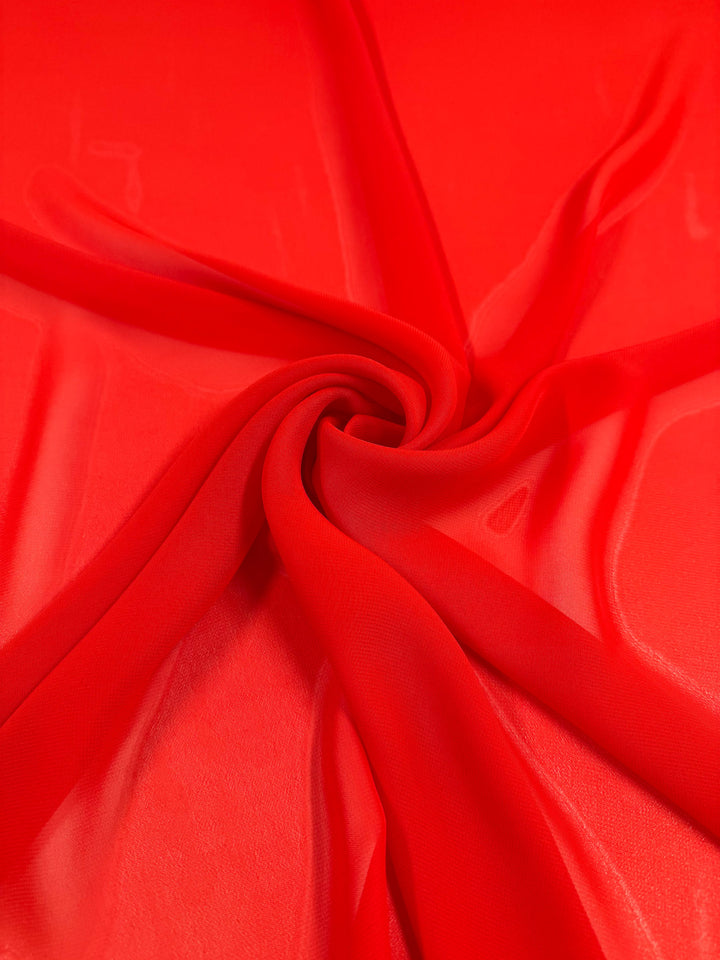 Hi-Multi Chiffon - Flame Scarlet by Super Cheap Fabrics is a bright red, lightweight, and slightly transparent sheer fabric arranged in a swirl to highlight its smooth texture. Width: 150cm.