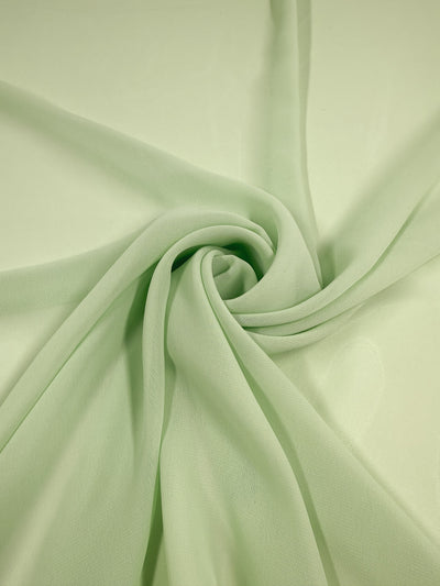 Super Cheap Fabrics' Hi-Multi Chiffon in pastel green (150cm) is a lightweight, delicate, and slightly sheer fabric with a soft texture that creates gentle folds and smooth, swirling patterns.