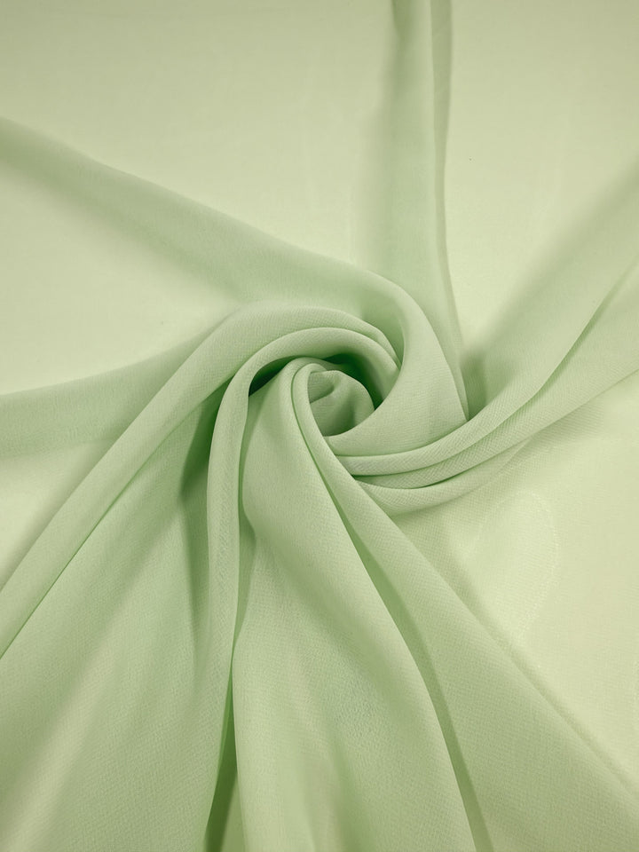 Super Cheap Fabrics' Hi-Multi Chiffon in pastel green (150cm) is a lightweight, delicate, and slightly sheer fabric with a soft texture that creates gentle folds and smooth, swirling patterns.