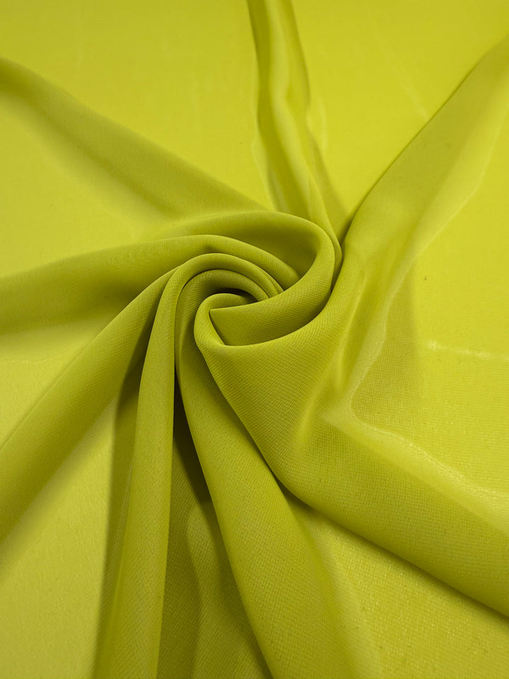Hi-Multi Chiffon - Apple Green - 150cm by Super Cheap Fabrics is a lightweight, slightly translucent fabric. Its apple green color and sheer texture, arranged in spiral folds, creates a soft, delicate look with added dimension.