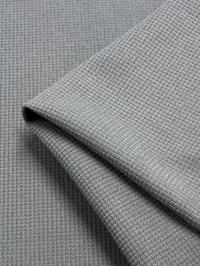 Close-up of Super Cheap Fabrics' Waffle Knit - Grey - 170cm, highlighting its soft material and intricate grid-like textured waffle pattern in light gray.