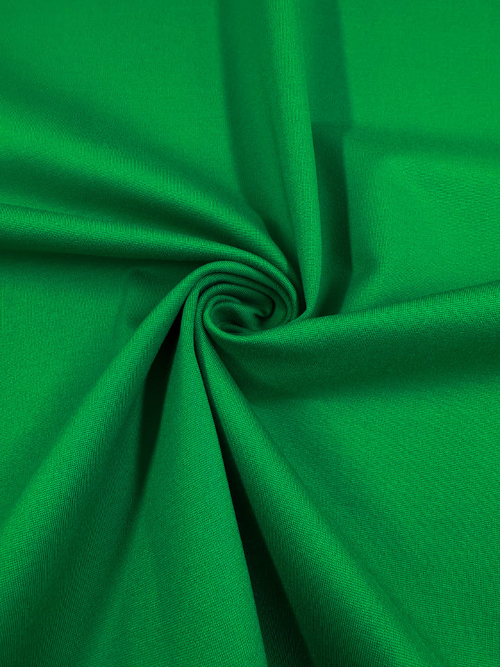 Super Cheap Fabrics' Milano Ponte - Jolly Green (160cm) is a bright green heavyweight fabric with a smooth texture, gathered and twisted at the center for gentle folds and a subtle spiral pattern.