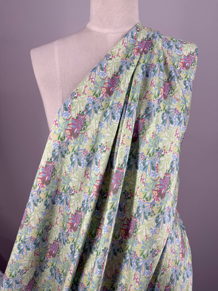 A dress form features "Garden Vine" mercerised rayon fabric by Super Cheap Fabrics, 150cm wide, in light green with a pink, blue, and white floral pattern, displayed against a plain mauve background.