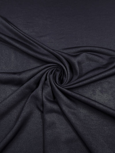 A close-up of Super Cheap Fabrics' Knit Lining - Dark Navy - 160cm, arranged in gentle folds to form a spiral and showcase the lightweight fabric's smooth, slightly shiny texture.