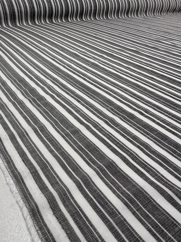 Close-up of Super Cheap Fabrics’ Linen Blend - Linen Stripe - 150cm, featuring black and white rayon linen with horizontal stripes of varying widths that form a geometric pattern across the fabric.