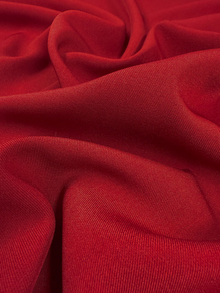 A close-up of Super Cheap Fabrics' Liquid Twill - Rythmic Red (150cm), showcasing its soft folds, smooth yet slightly textured twill surface, with gentle shadows and highlights that emphasize the quality of the fabric.