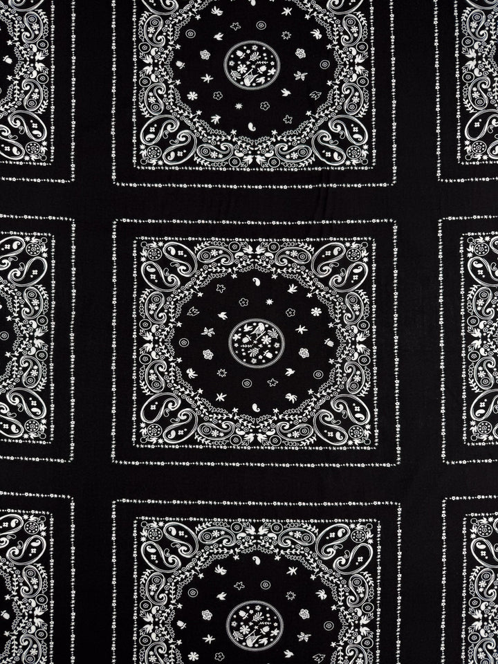 Super Cheap Fabrics' Designer Rayon - Bandana Noir (148cm) is a black lightweight rayon fabric with white paisley bandana patterns featuring swirls, dots, stars, and florals in square and circular designs.