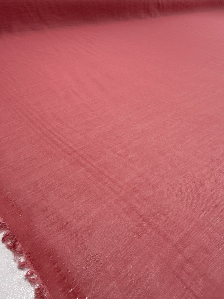 A close-up of Super Cheap Fabrics' Designer Voile - Rose of Sharon (150cm), a soft, dusty rose pink lightweight fabric with slightly sheer texture and raw edges—ideal for summer dresses.