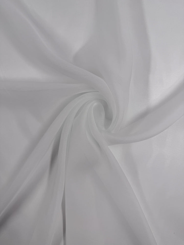 Super Cheap Fabrics’ Designer Voile - White - 150cm features sheer white fabric twisted into a spiral pattern, forming soft folds and a delicate, translucent look against light backgrounds.
