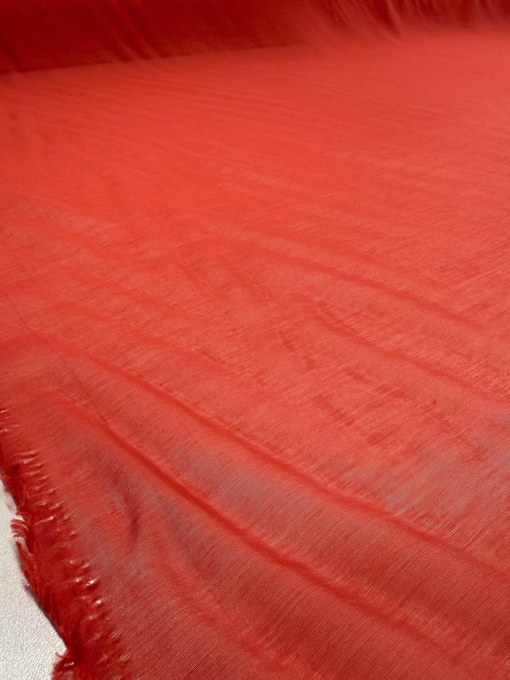 A close-up of Super Cheap Fabrics’ Designer Voile - Paprika - 150cm, a lightweight fabric with visible texture and slightly frayed edges, ideal for sheer summer dresses.
