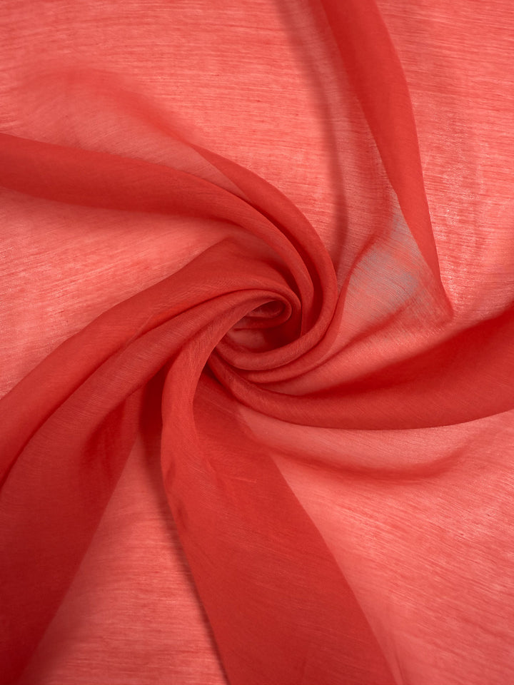 Designer Voile - Paprika - 150cm from Super Cheap Fabrics features sheer red fabric with a swirling spiral pattern, making it ideal for airy summer dresses with soft folds and subtle shade variations.