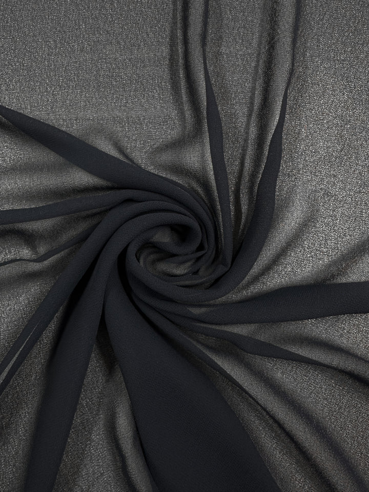 A close-up of Super Cheap Fabrics’ Hi-Multi Chiffon in Navy (150cm) shows its sheer polyester texture, soft folds, and subtle shimmer arranged in a spiral pattern.