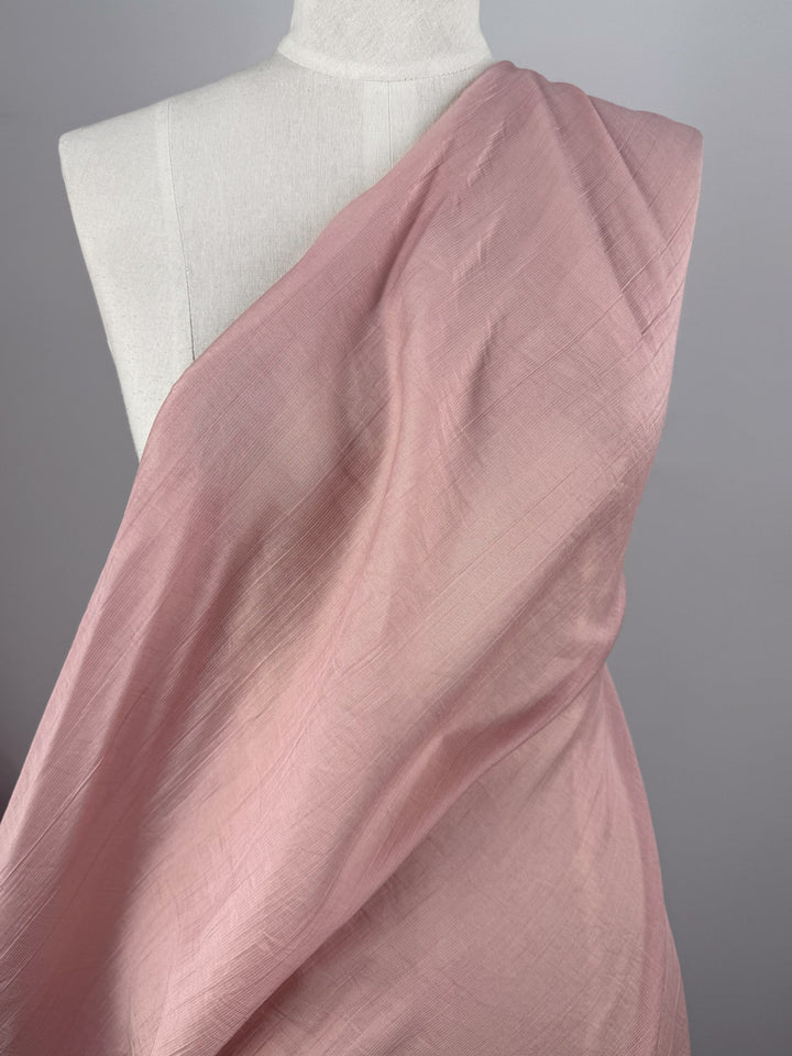 A mannequin showcases Super Cheap Fabrics' Textured Designer Voile - Silver Pink (155cm), a soft, subtly shiny fabric ideal for summer dresses or any style needing a delicate, lightweight touch—displayed on a plain gray background.