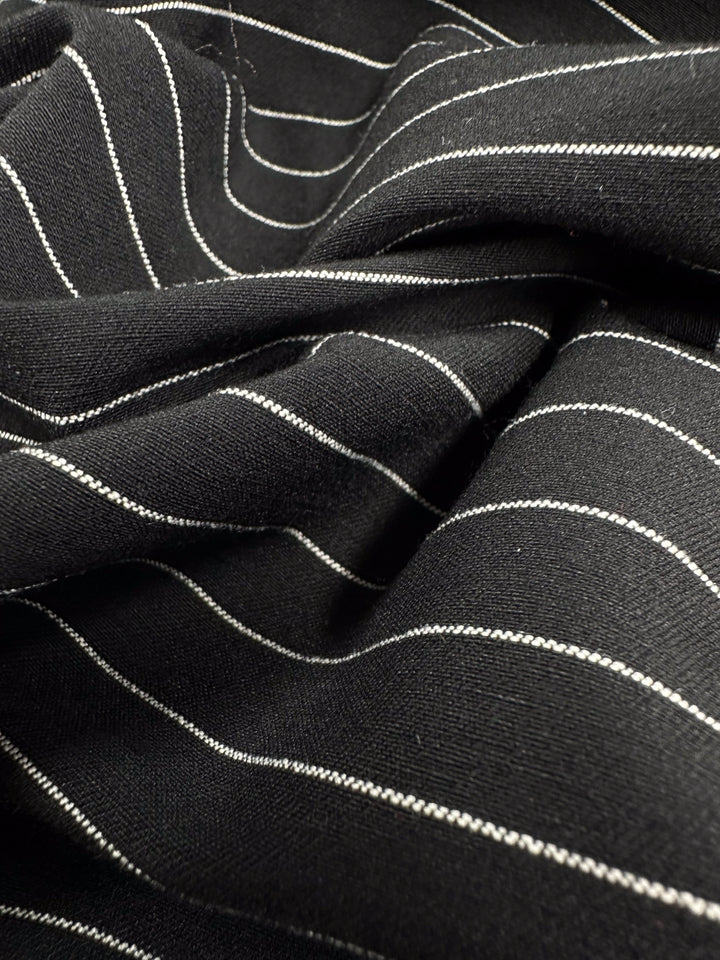 A close-up shows the folds and texture of Super Cheap Fabrics' Printed Bengaline in Ivory Pin Stripe (145cm). The slightly wrinkled surface highlights the fabric's regular pinstripes, making it ideal for skirts and dresses.