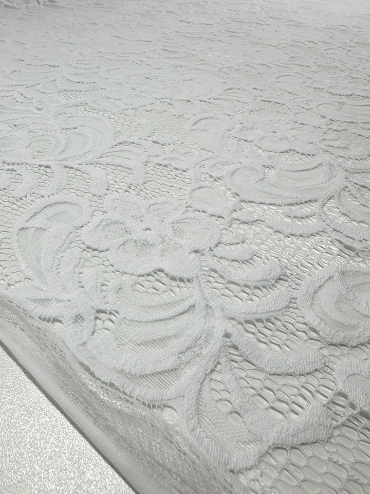 Close-up of Designer Lace - White - 145cm by Super Cheap Fabrics, showcasing an intricate floral pattern and delicate weaving, ideal for evening dresses. The lace spans the entire image, highlighting its elegant design.