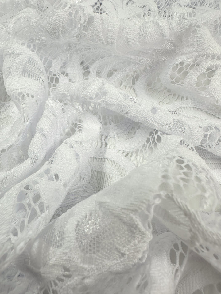A close-up of Super Cheap Fabrics' Designer Lace in White (145cm) reveals intricate floral and geometric patterns perfect for evening dresses, with a delicate texture of sheer and solid areas for an elegant, airy look.