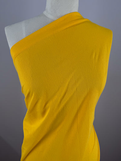 A mannequin showcases a one-shoulder garment crafted from Super Cheap Fabrics' Cotton Jersey in Citrus (155cm), set against a soft gray backdrop.