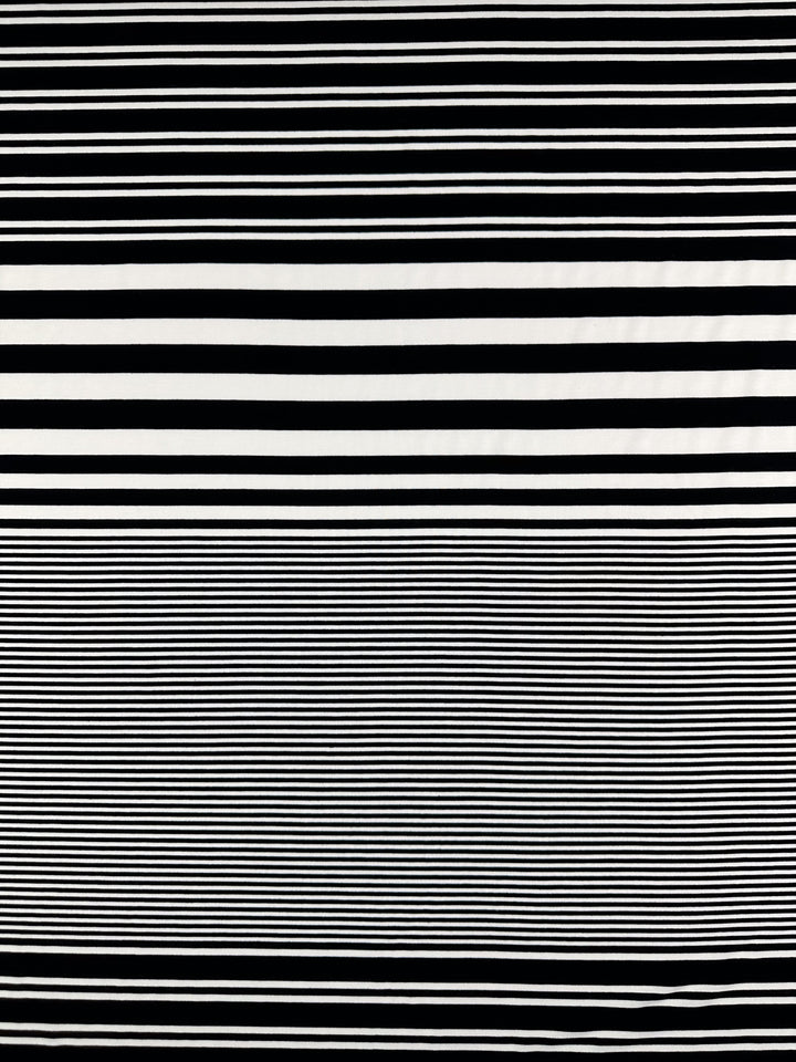The Viscose Jersey - Paralello - 160cm by Super Cheap Fabrics showcases a dynamic pattern of horizontal black and white stripes, with wider ones on the top half and thin, closely spaced stripes on the bottom half, all on a soft, stretchy fabric.