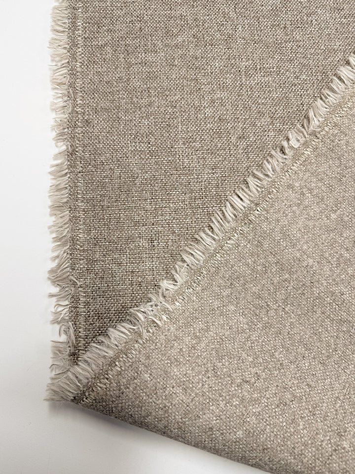 A close-up of Super Cheap Fabrics' Upholstery - Soho Cinnamon - 150cm, featuring its medium weight, wool-look texture and fringed edge, shown folded at one corner on a white background.