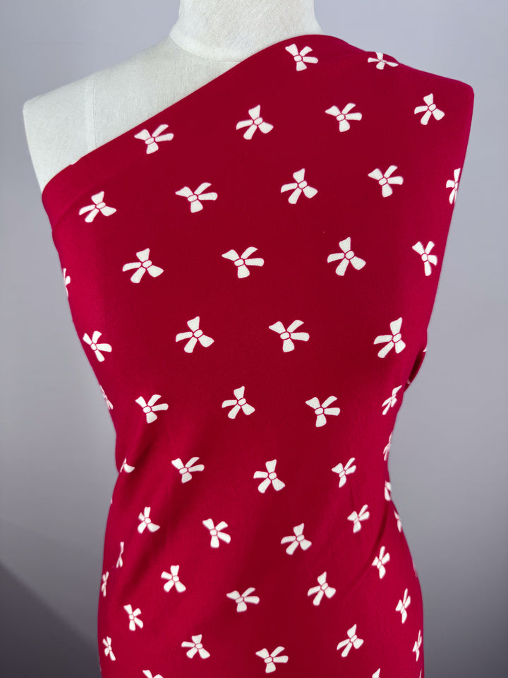 Displayed on a mannequin, the Urban Red dress by Super Cheap Fabrics is crafted from medium-weight Printed Cotton Lycra with a white floral pattern. It boasts a chic one-shoulder design against a plain gray background.