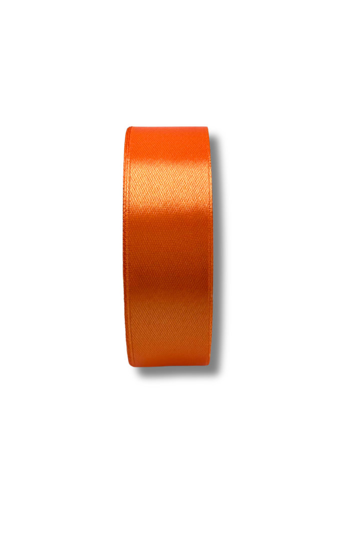 A roll of Super Cheap Fabrics Satin Ribbon - 16 Colours - 25mm, in shiny orange, stands upright on a plain white background, casting a faint shadow to the right.