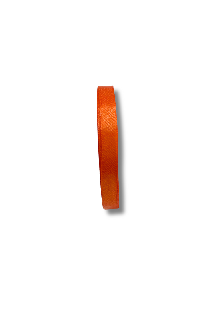 A 10mm wide orange "Satin Ribbon - 10 Colours" by Super Cheap Fabrics forms a vertical loop against a white background, casting a soft shadow to the right.