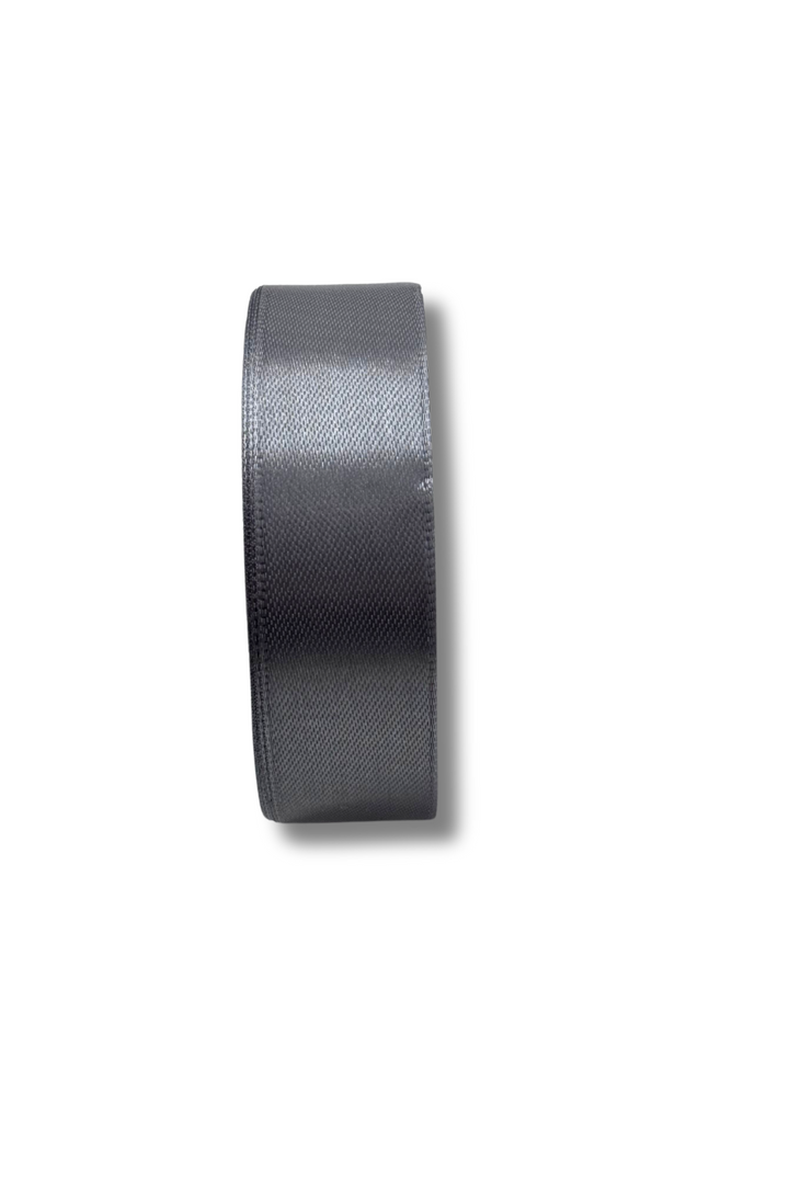 A Super Cheap Fabrics Satin Ribbon in black (25mm wide) is shown from the side, highlighting its smooth, slightly shiny finish against a plain white background.