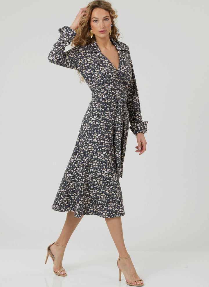 A woman with long wavy hair poses confidently in the Super Cheap Fabrics Pattern - Vogue V2000 Misses’ DVF Wrap Dress by Diane von Furstenberg, paired with nude heels, against a plain white background.