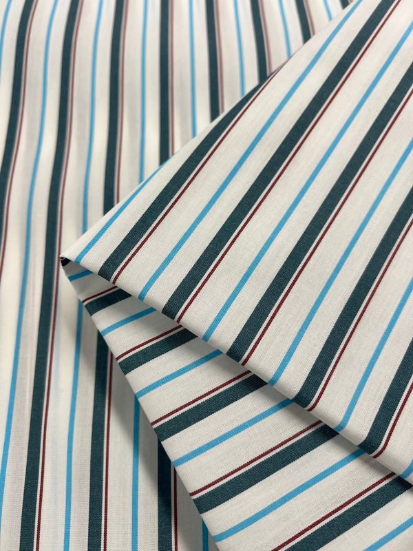 Shirting - Marquee - 150cm by Super Cheap Fabrics is a folded, lightweight polyester cotton with black, blue, red, and white vertical stripes on a light base—ideal for dresses, its neat folds accentuate the colorful stripe pattern.
