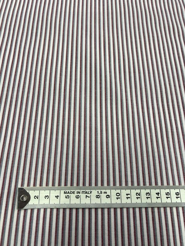 A close-up of Super Cheap Fabrics’ Shirting - Hearted - 148cm, a lightweight polyester viscose blend with thin red and blue vertical stripes on white, is shown beside a centimeter-marked tape and labeled "MADE IN ITALY.