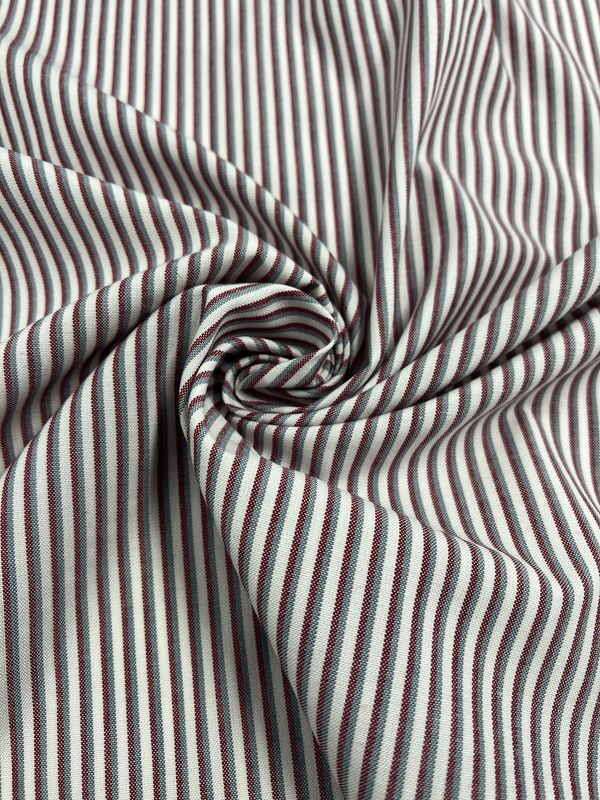 A close-up of Shirting - Hearted - 148cm by Super Cheap Fabrics, featuring lightweight fabric with narrow vertical maroon and white stripes, gathered at the center for a swirling pattern and soft folds.