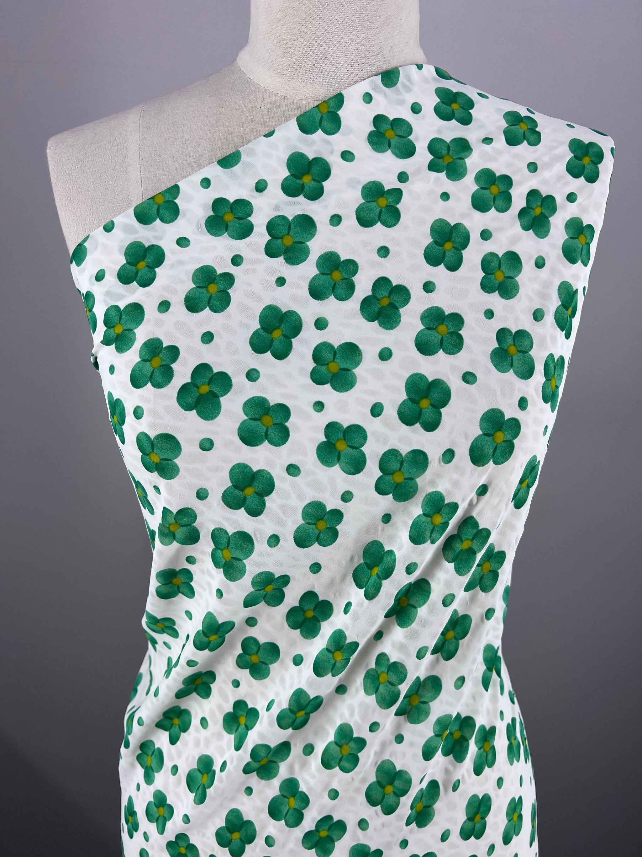 The dress form displays our new Salt Shrunk Print - Clover fabric from Super Cheap Fabrics, featuring green four-leaf clovers and small green dots on a white background arranged asymmetrically over the shoulder, accentuating its vibrant design. Width: 155cm.