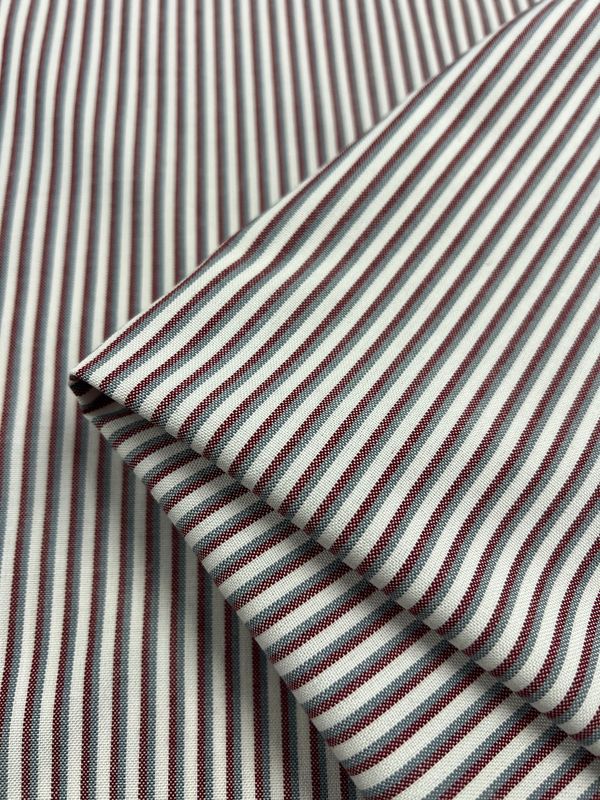 Close-up of Shirting - Hearted - 148cm by Super Cheap Fabrics, featuring lightweight polyester viscose with thin vertical maroon and white stripes, neatly folded to highlight the detailed weave and pattern.