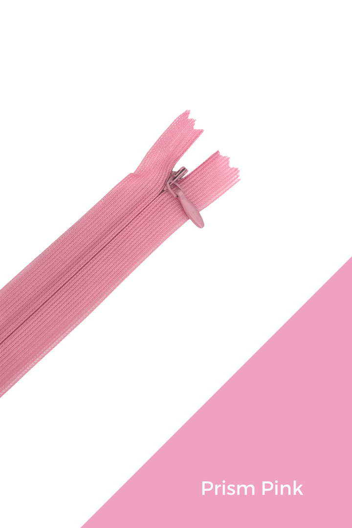 The Super Cheap Fabrics Invisible Zip - 30cm - Pinks & Reds is shown diagonally on a white and pink background. A pink block in the lower right displays "Prism Pink" in white text. The zipper is pink and made from 100% polyester.