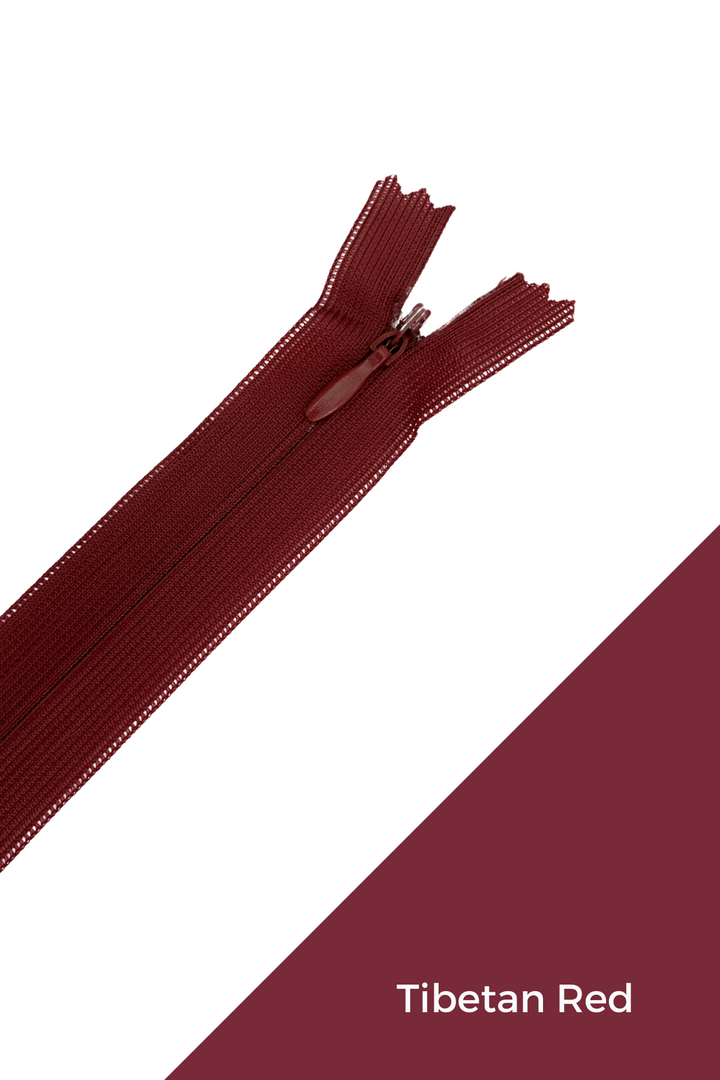 A Super Cheap Fabrics Invisible Zip - 30cm - Pinks & Reds in maroon polyester lies diagonally on a white background, with a matching "Tibetan Red" swatch labeled in white at the lower right corner.